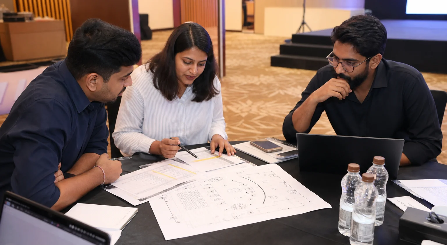 An event planning meeting with a run-of-show, floor plan and laptops